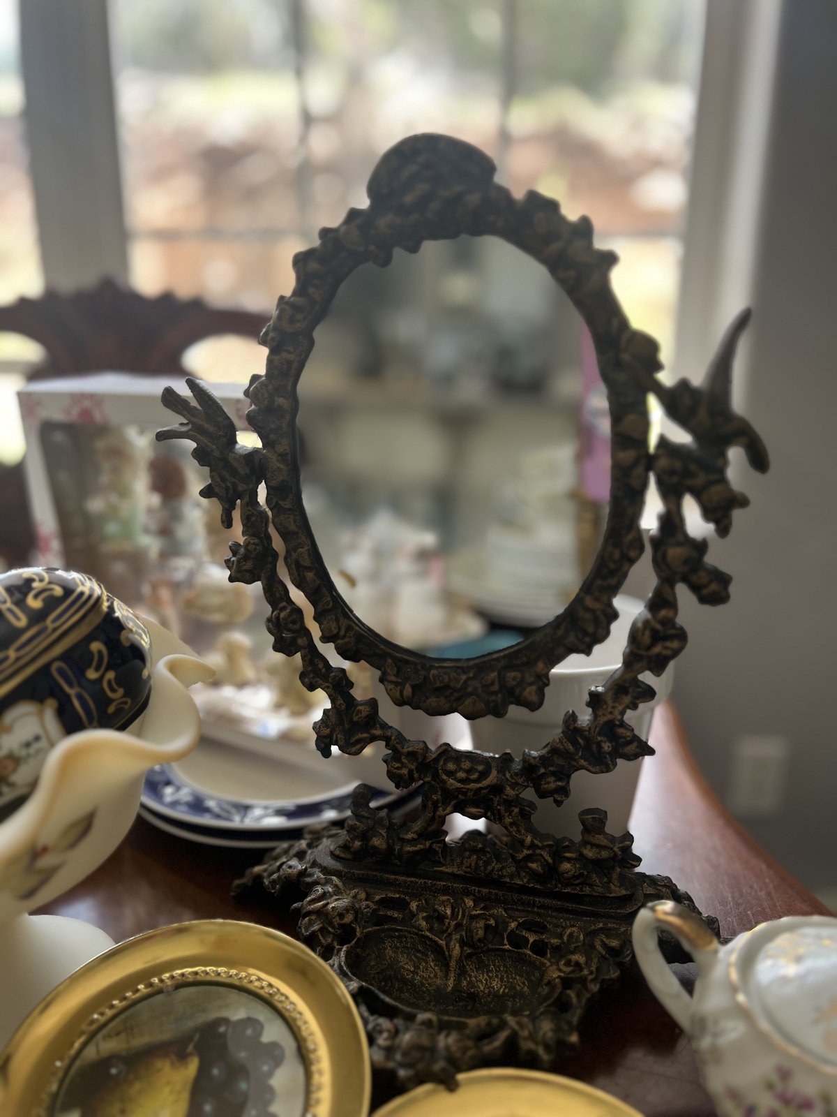 Ornate bronze vanity mirror with bird and floral cast frame