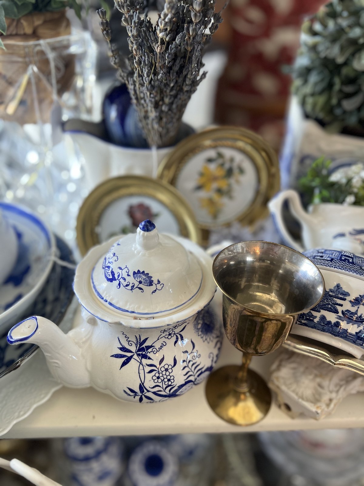 Blue Onion pattern porcelain teapot beside a brass goblet